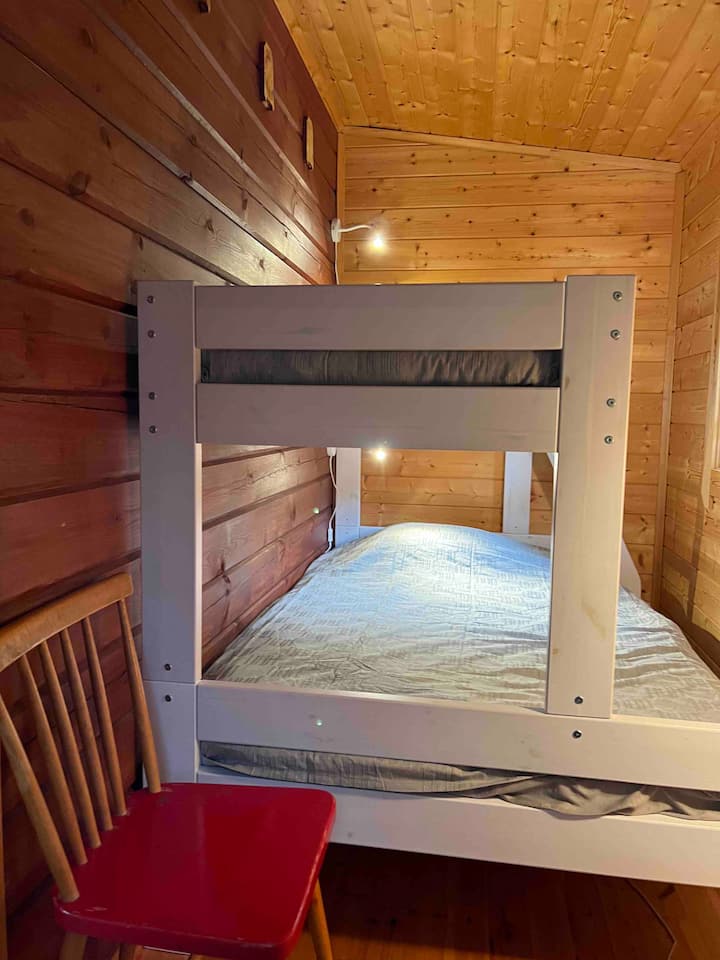 Malá spálňa s dverami v dolnej saune/chate, poschodová posteľ, spodná posteľ 120 cm, horná posteľ 80 cm.