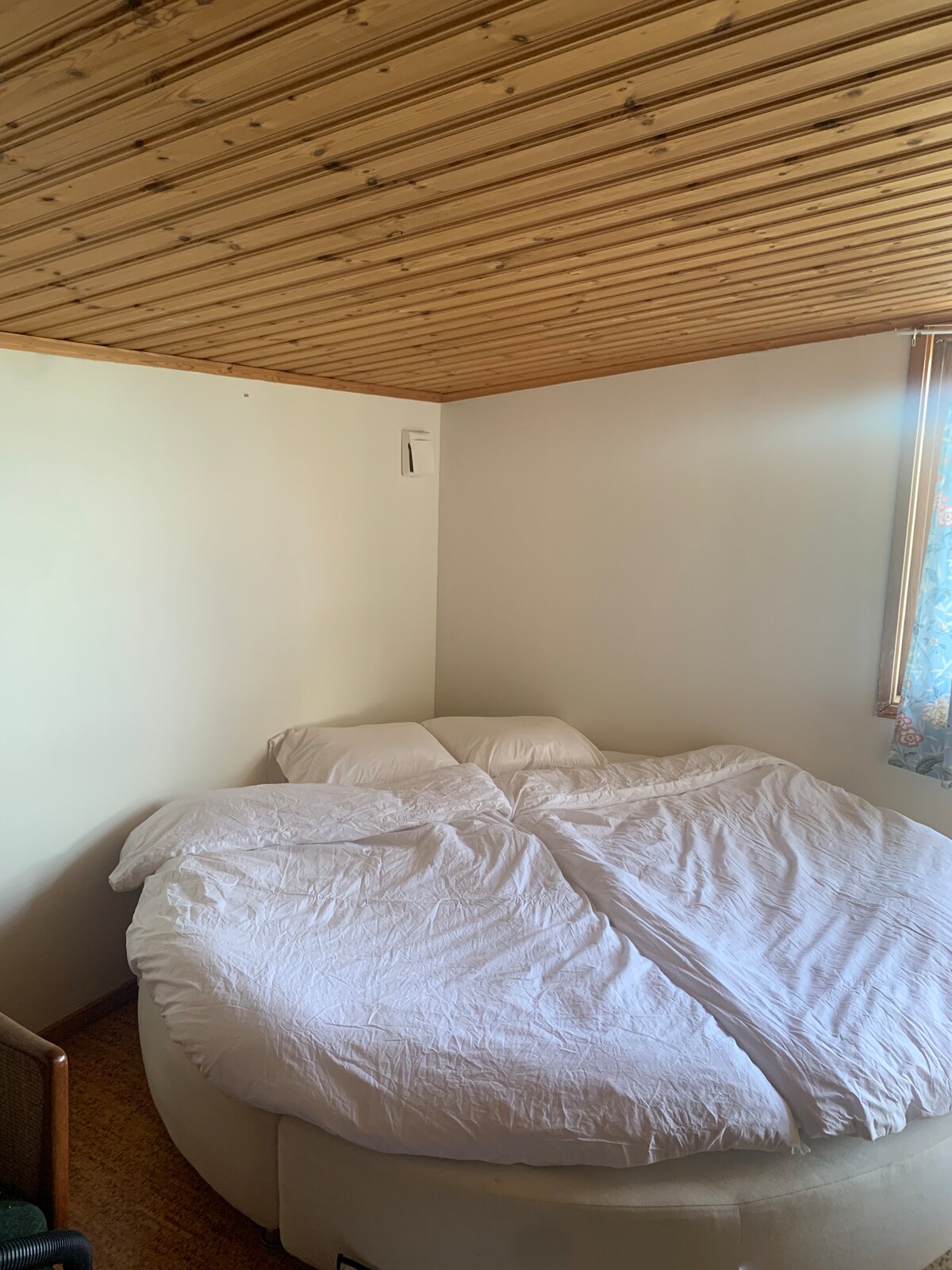 Okrúhla posteľ. V tejto izbe sa nachádza aj umývadlo a ďalšia posteľ. 