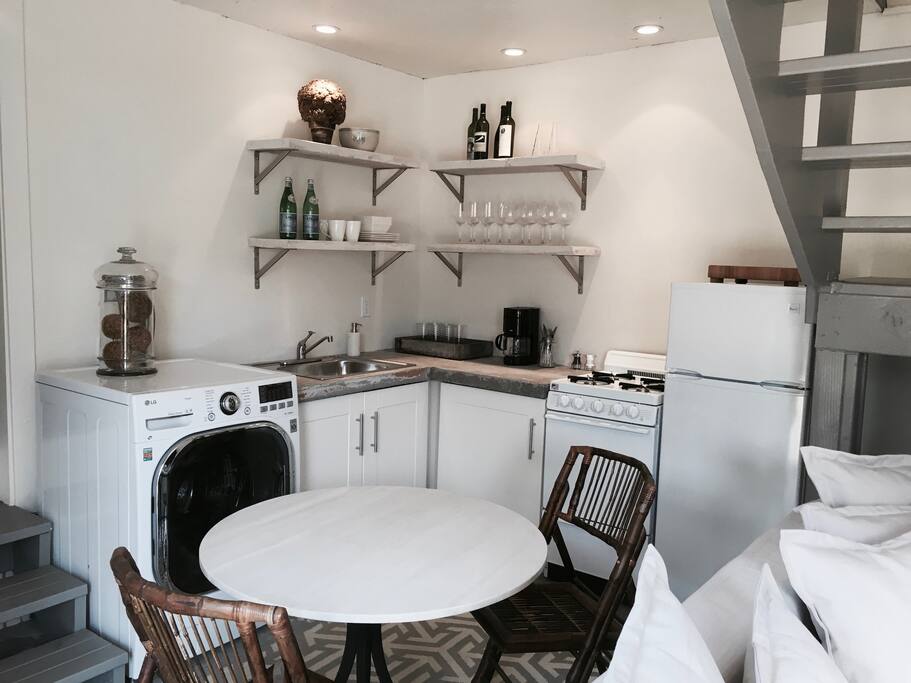 A petite chef's kitchen offers custom concrete countertops and brand-new appliances, including a gas-top stove, refrigerator, and an LG washer/dryer.