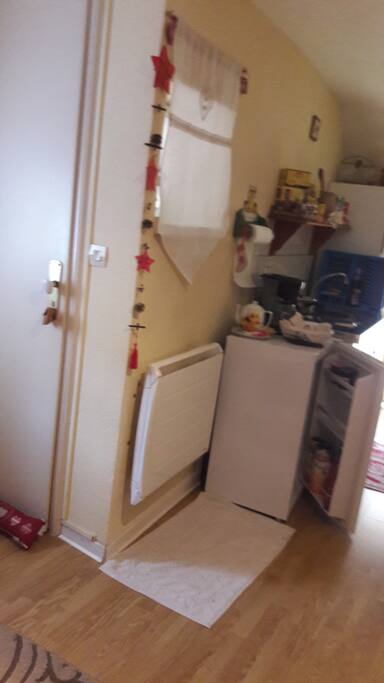 La porte d'entrée avec le chauffage murale. et le coin cuisine