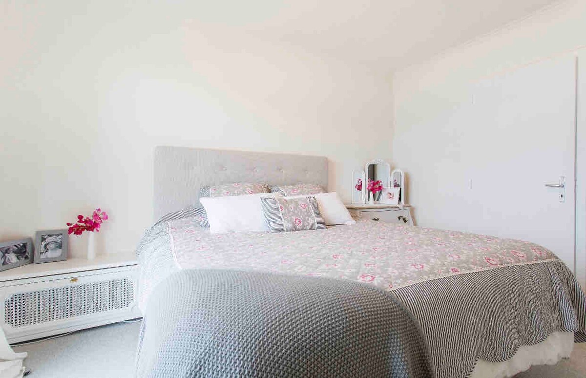 Chumba cha kulala cha wageni kilicho na kitanda cha King cha ukubwa wa watu wawili, kiti na kabati. Dirisha la Kifaransa linafunguka kwenye roshani