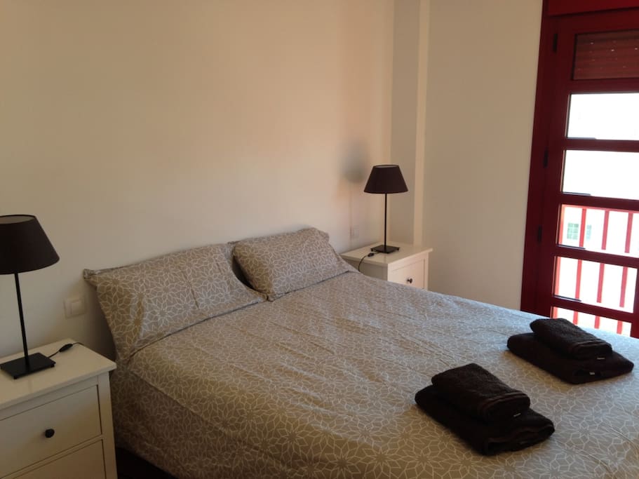 Dormitorio con cama de 150 cms. y pequeño balcón.