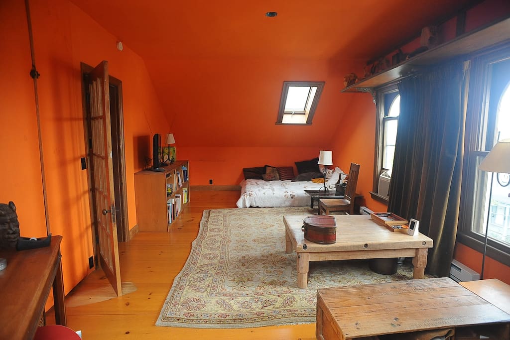 Spacious Main Bedroom with a queen sized bed in a private room with skylights, a sitting area and a wooden desk.