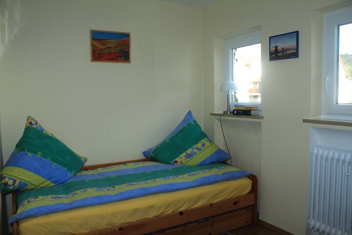 втора спална соба со два единечни кревета и полица