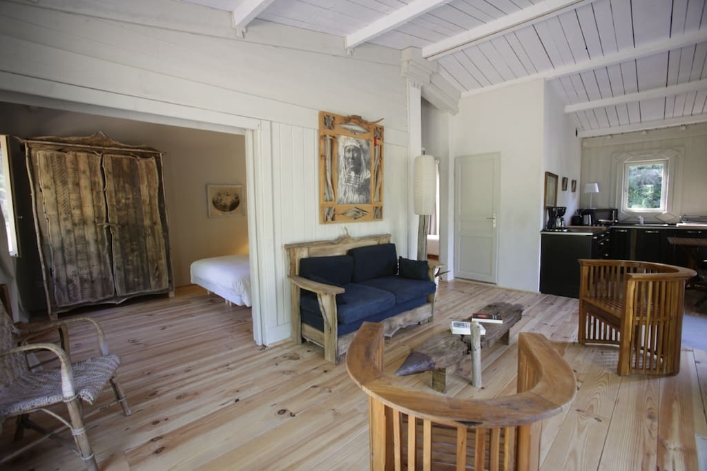 Vue du salon de la cabane du mont Paon donnant sur la chambre avec le lit double porte coulissante ouverte.