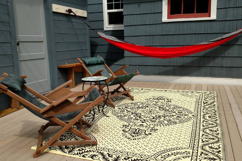 Backyard deck with lounge chairs, benches, and hammock.