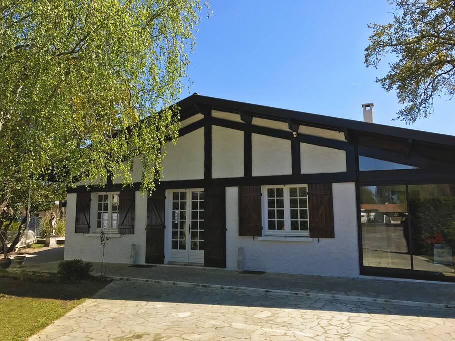 Terrasse de jardin avec piscine, transats, chaises, mobilier d'extérieur et douche solaire.