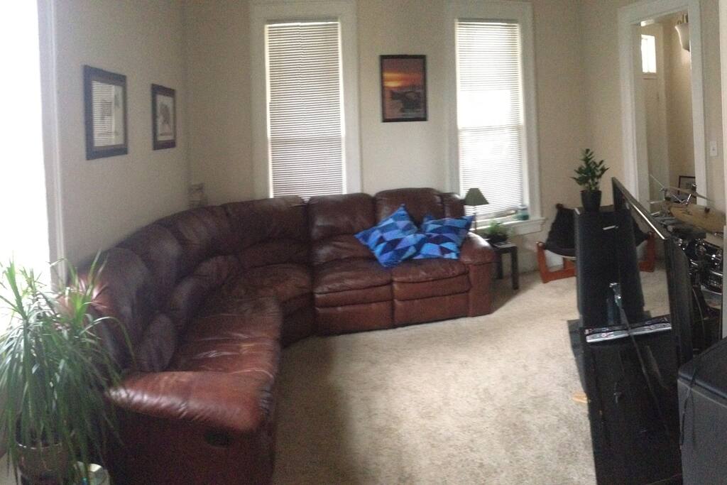 Living room with large rap around leather couch. With flat screen tv, Sony floor speakers and surround sound system.