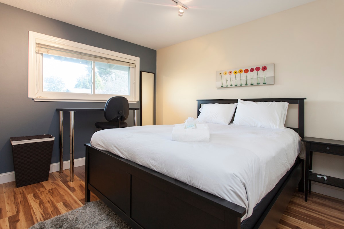 Druhá spálňa s manželskou posteľou Queen, písacím stolom a veľkým oknom.