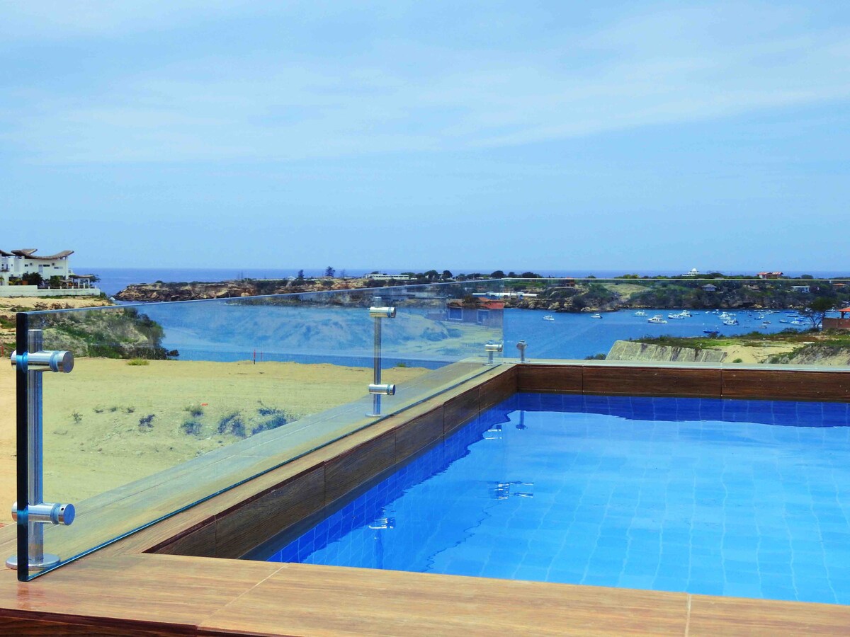 A private pool is positioned on the terrace, offering clear views of the bay and surrounding landscape. The water reflects the sky, while the pool's edge is framed by glass railings, ensuring an unobstructed line of sight to the serene waters beyond.