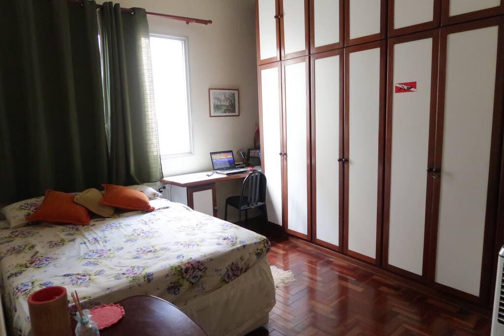 Quarto com cama de casal e área de trabalho