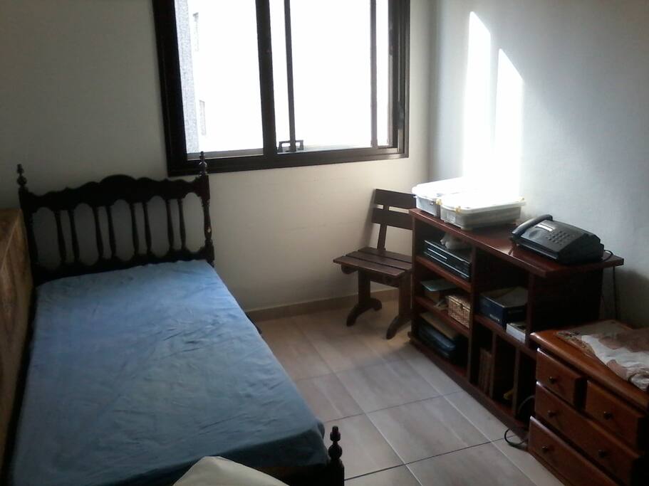 Dormitorio com uma cama de solteiro, armario embutido e aparador.