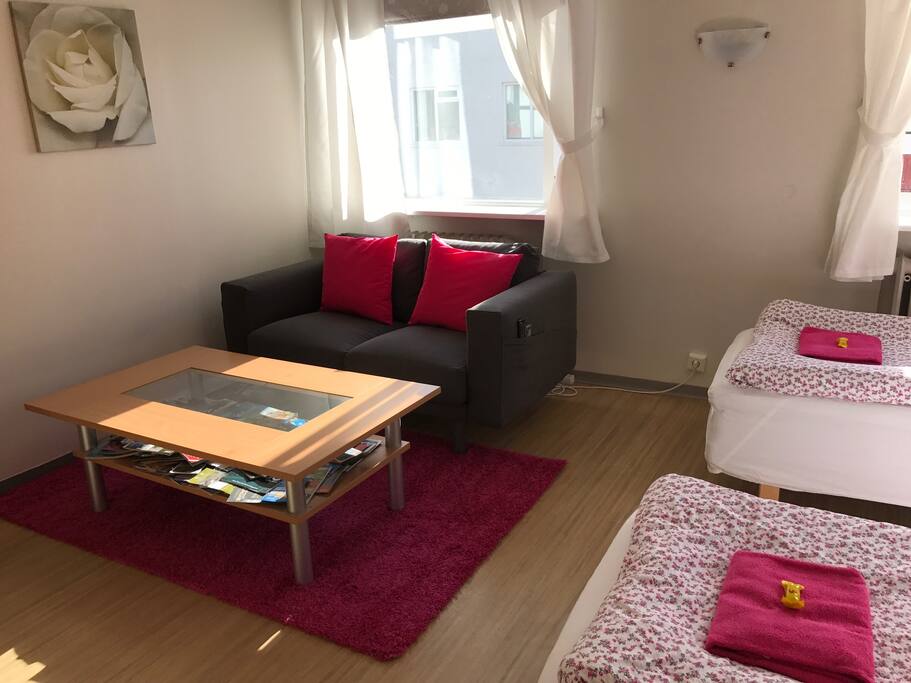 here is a couch, cupboard and table in the room together with the two beds.