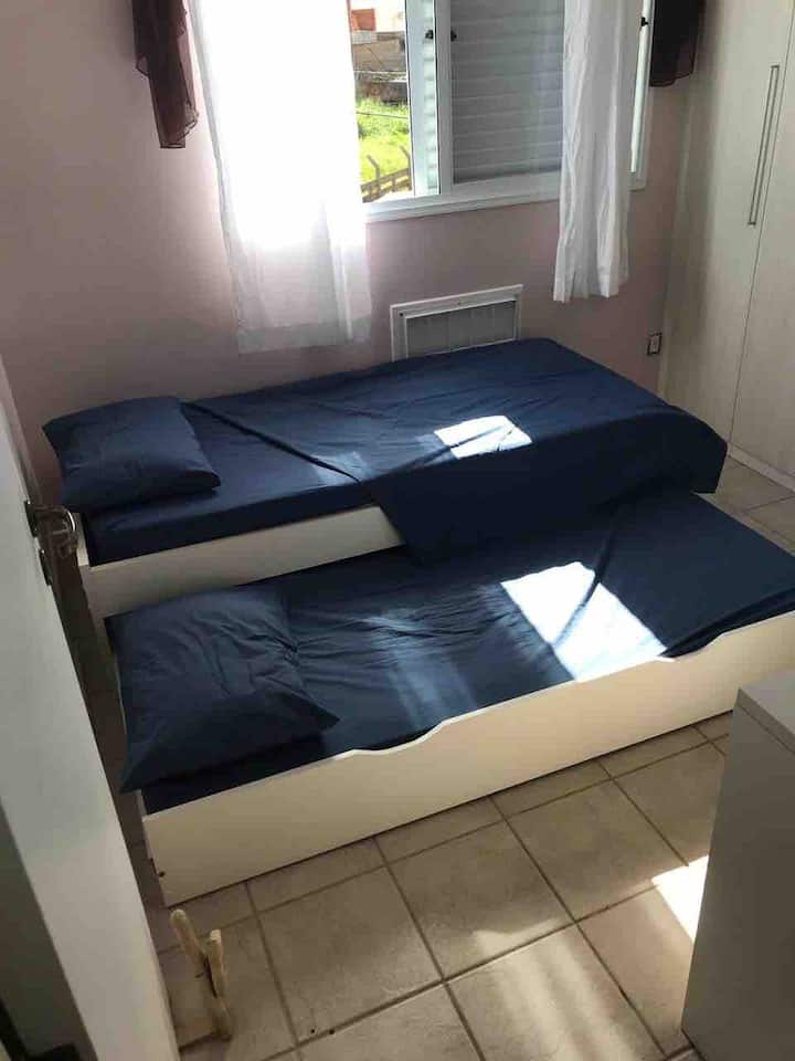 חדר שינה יחיד עם מיטה נפתחת + מלתחה עם מגירות, קולבים ומדפים + שולחן מחשב נייד.