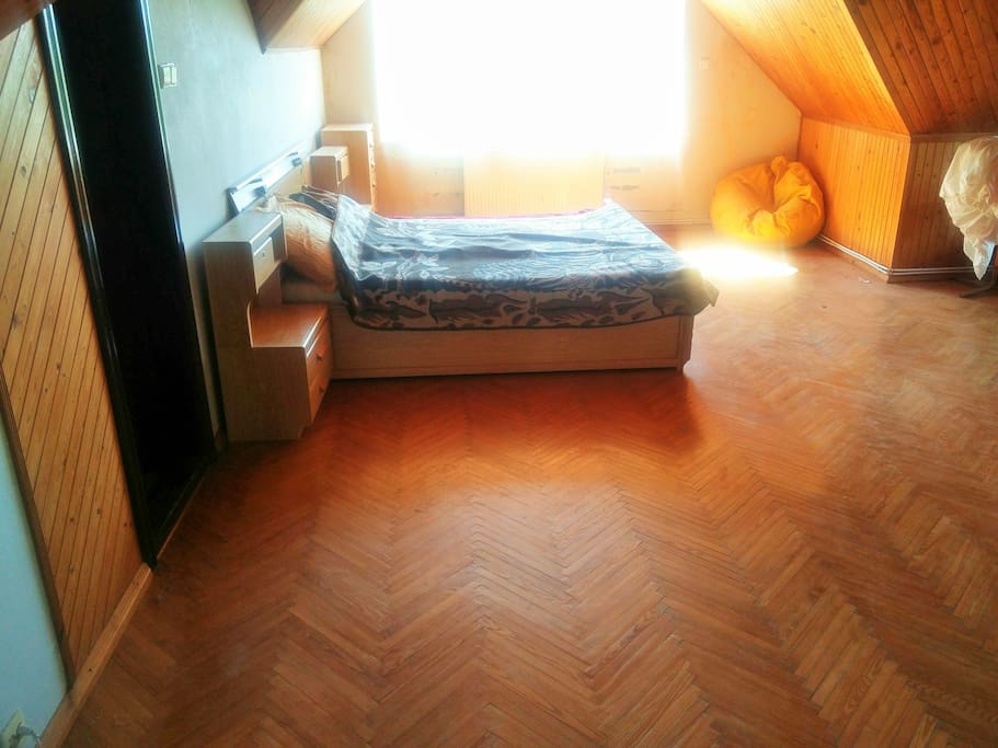 The bedroom being offered. Its on the third floor of the house, with a double bed, puffy chair, some cupboards at the sides and a window where morning light shines in