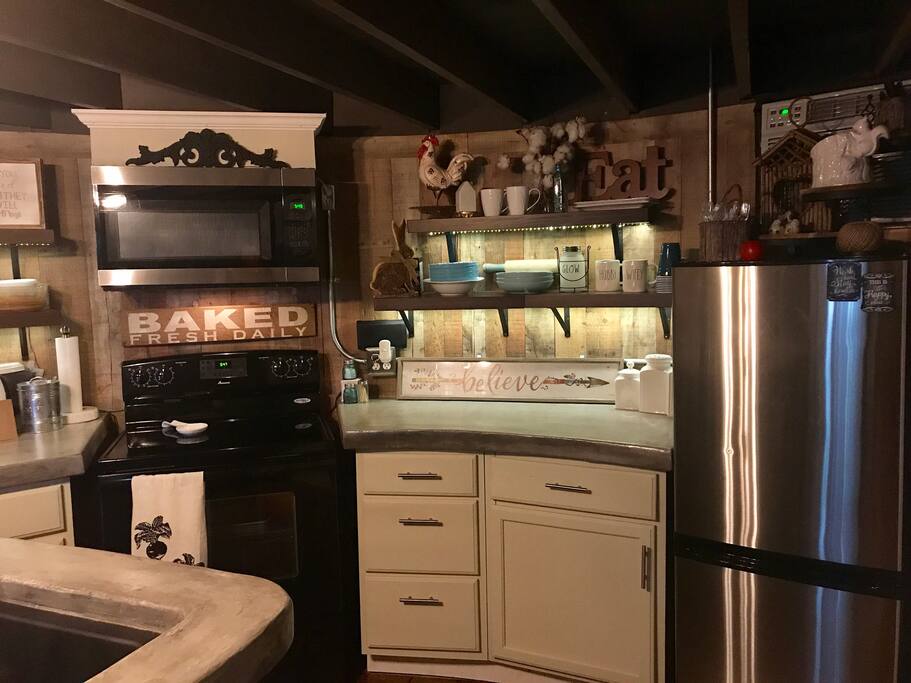 Kitchen has a full size range, microwave, refrigerator. Kitchen is fully stocked with dishes, cookware, and silverware. Bar top and countertops are made of concrete, custom built by my husband.