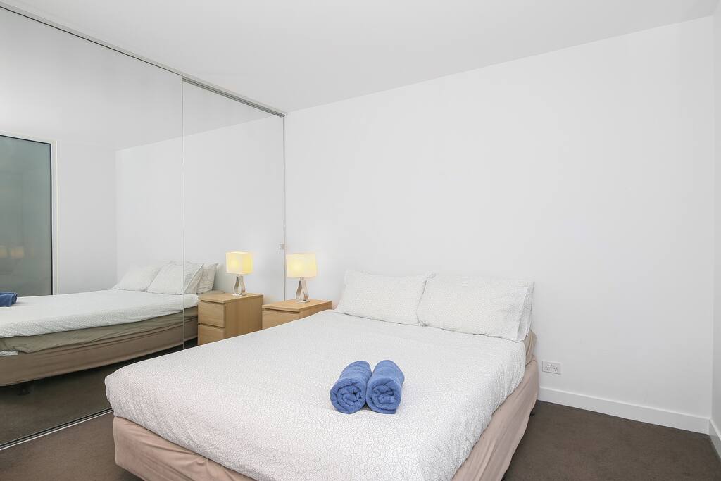 A bedroom with a queen sized bed & plush pillows.