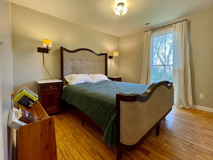 Glavna spavaća soba s prozorom od poda do stropa, bračnim krevetom,  ormarom i malom besplatnom knjižnicom.