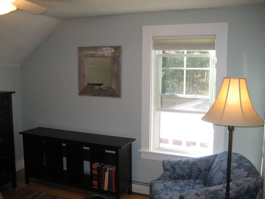 Window looking over the woods and cozy reading chair.
