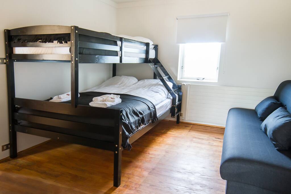 Room with a bunk bed (double below and a simple upstairs) and a studio couch for two.