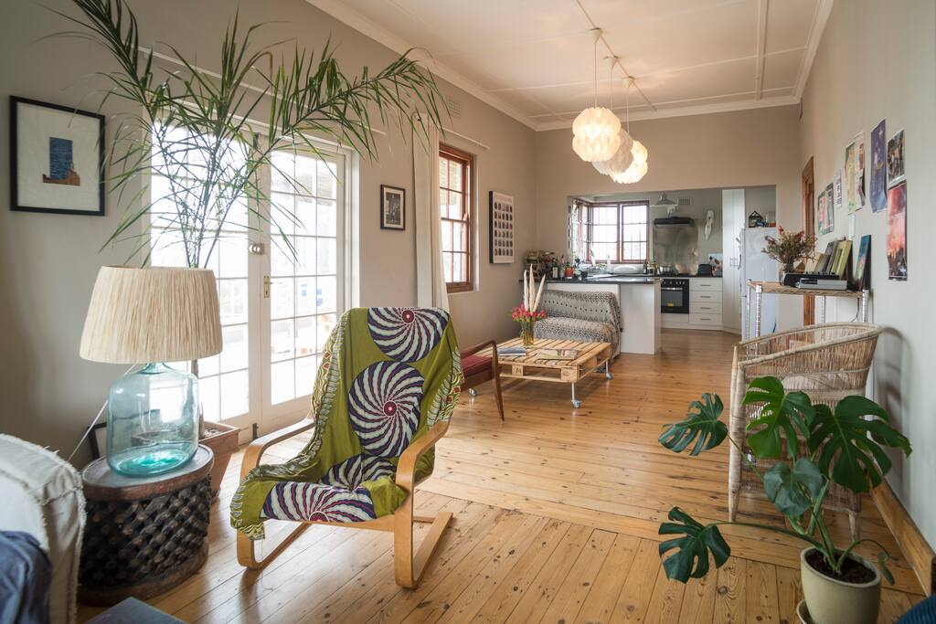 Expansive living area with an array of pot plants, comfortable furniture, vinyl player and flatscreen TV.