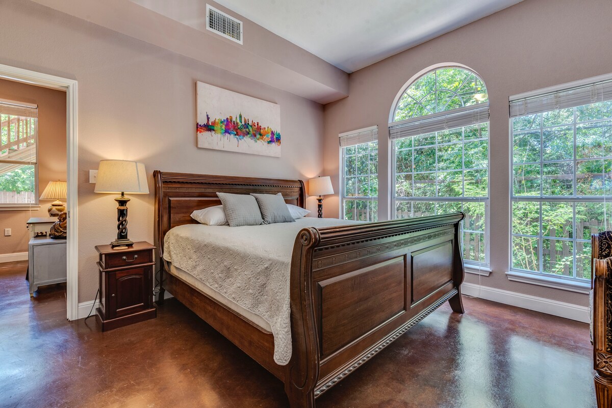 Ogromna, raskošna spavaća soba s velikim prozorima i mirnim pogledom na zeleni pojas 