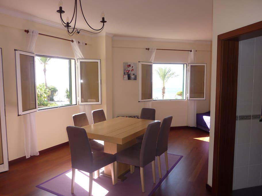 Spacious sunny lounge and dining area with two windows with ocean views
