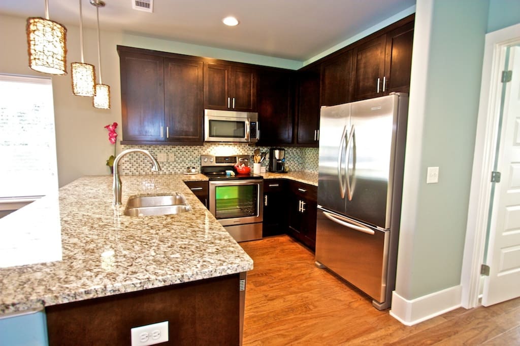 Kitchen is well appointed with granite and stainless steel appliances, and filled with warm natural light
