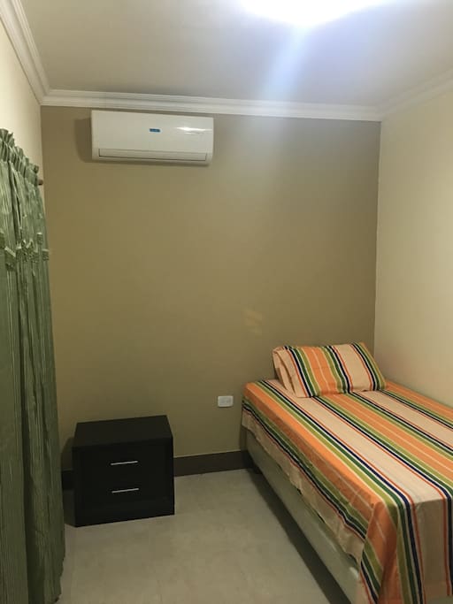 Dormitorio con 1 cama de dos colchones, aire acondicionado y velador.