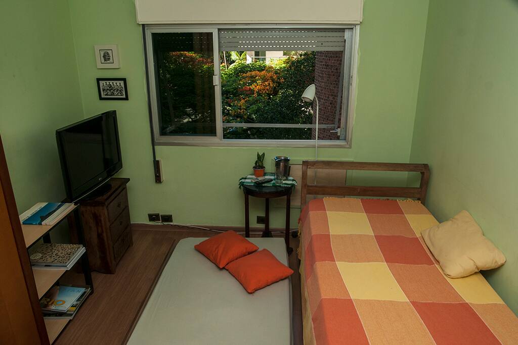 Quarto com armário, televisão e ventilador de teto.