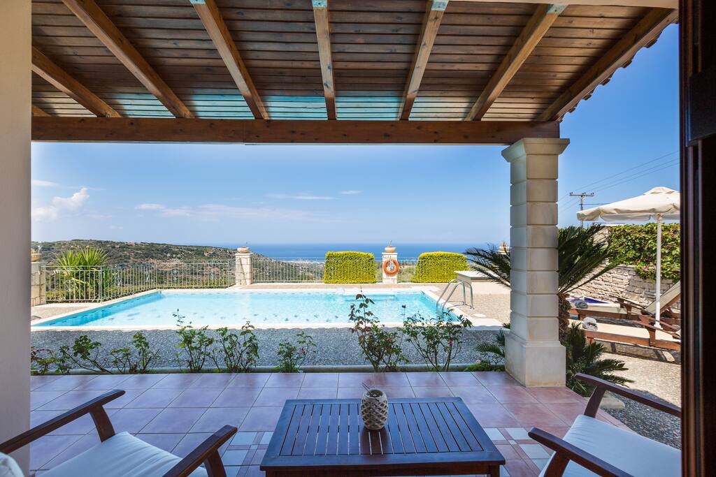 Sitting area under a pergola next to the pool with sea views