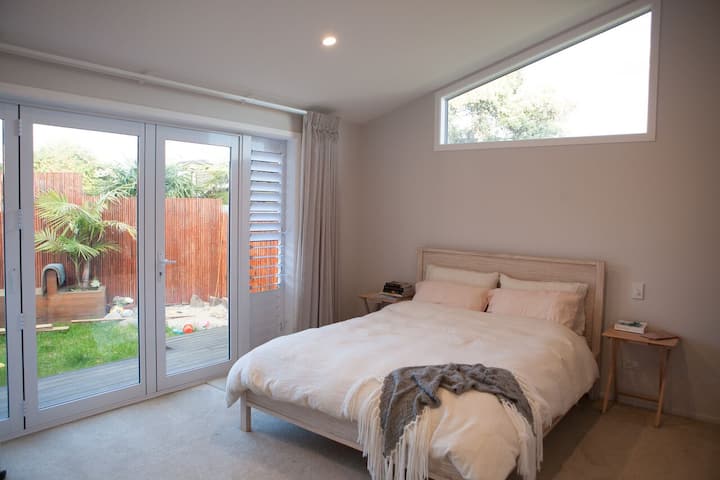 Ditt huvudsovrum med dörrar som öppnar mot det bakre däcket och trädgården