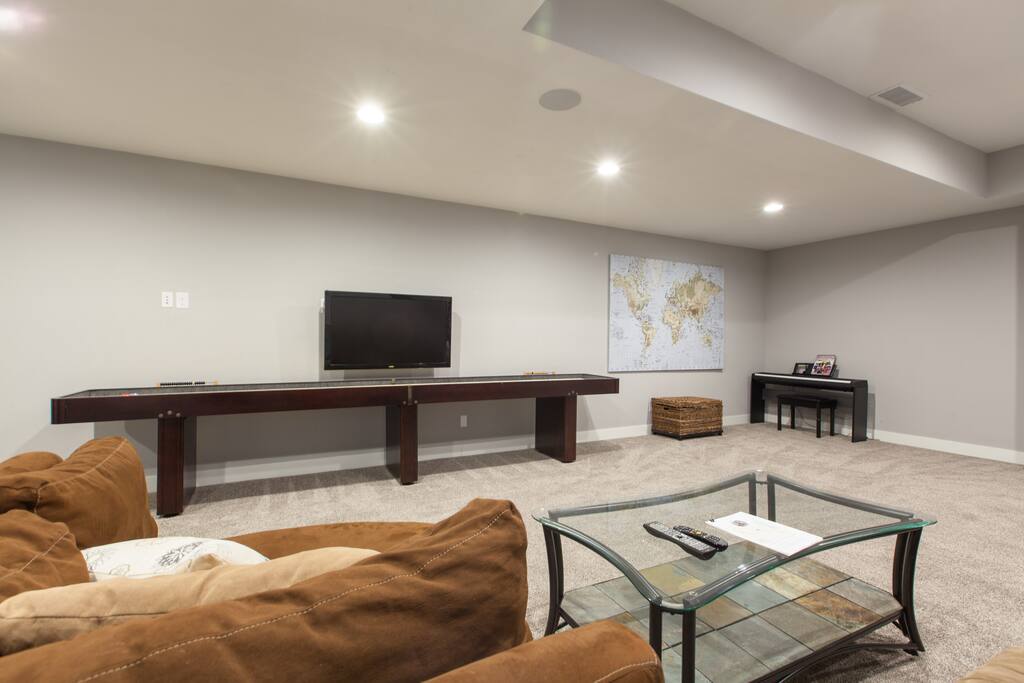 Spacious and private basement living room with shuffleboard table, TV, games and more. TV has cable and internet access for Netflix