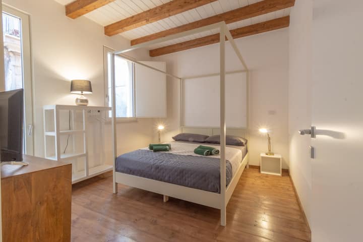 Dvokrevetna spavaća soba s vrlo svijetlim krevetom s četiri postera zahvaljujući velikom prozoru i staklenim vratima koja vode do balkona iznad prekrasne uličice Giudecca