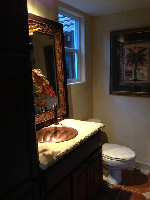 Bathroom features chiseled counter w/ copper sink, travertine and washer/dryer.