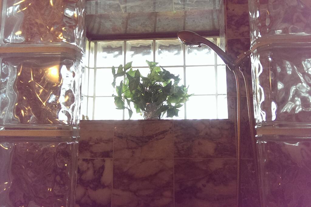 The marble shower has a glass block window with a copper covering.