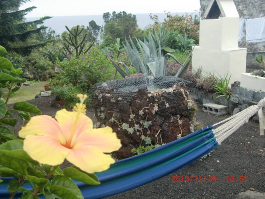 garten mit hängematte und hochteich aus lavasteinen