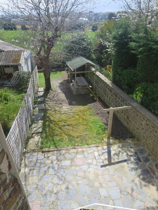 Accessible du rdc par quelques marches, partie dalée, tout petit potager, étandage à linge, salon de jardin abrité, cerisier, cabane dans le laurier sauce, sortie sur rue pietonne à l'arrière, clos