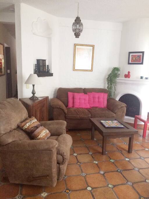 La sala tiene un cómodo love seat y un sillón individual reclinable con vista al balcón y jardín arbolado.