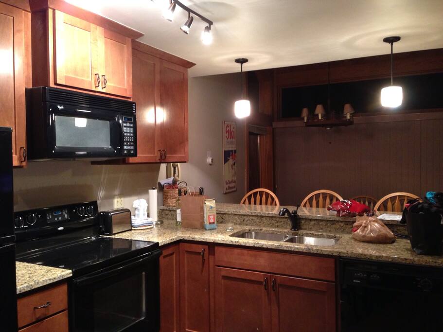 Kitchen, looking out onto dining room and living room with fireplace.
