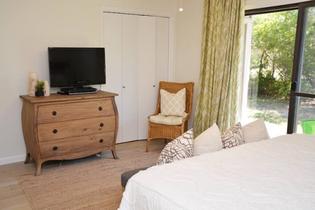 Master bedroom with flat screen tv, patio, and washer and dryer on patio in closet