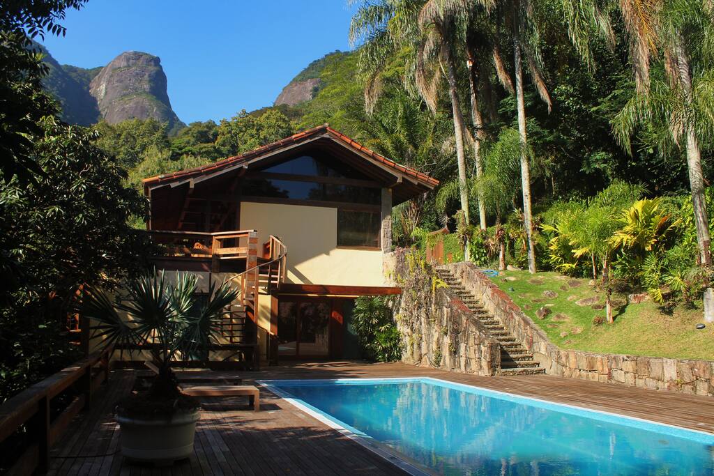 A casa vista de quem está no deck da piscina. Com toda exuberância da Mata Atlântica e a mítica Pedra da Gávea atrás.