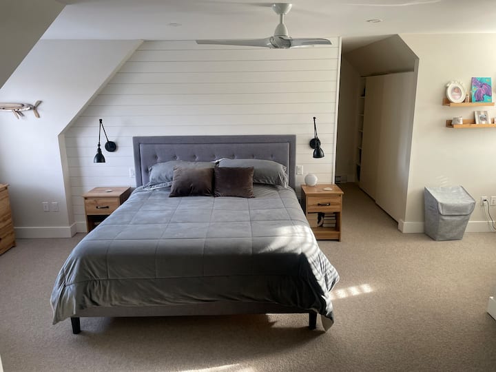 ห้องนอนใหญ่ขนาดใหญ่/ห้องพักผ่อนสำหรับผู้ปกครองพร้อมเตียงคิงไซส์และเลานจ์/โซฟาเบดที่มุมห้อง ทีวี 4K โต๊ะเขียนหนังสือ เก้าอี้นั่งสบาย และหน้าต่างบนผนัง 3 ด้านที่มองเห็นวิวภูเขาท้องถิ่น