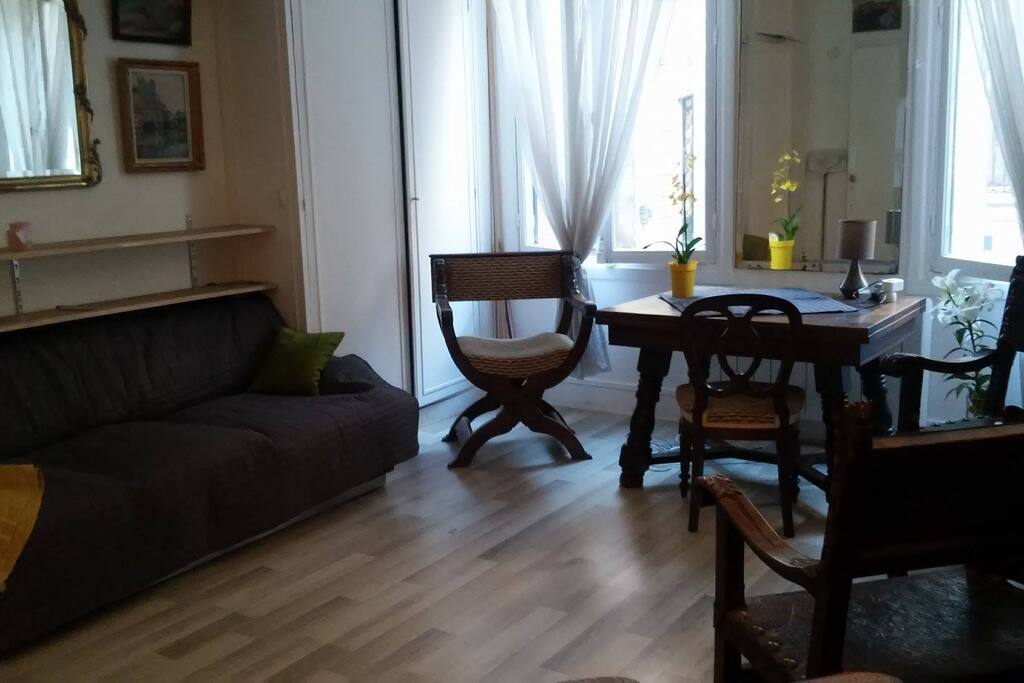 Canape bed with desk/table. Windows open on the street.
