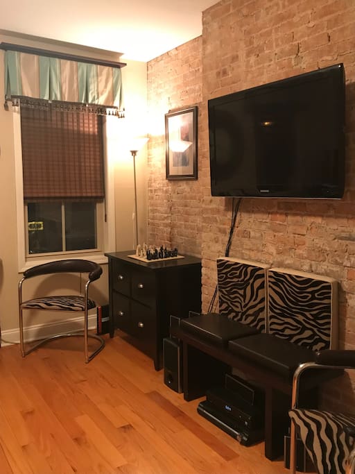 TV Room. Sofa couch, Two Chairs, Bench, Flat Screen TV, Bookshelf.
