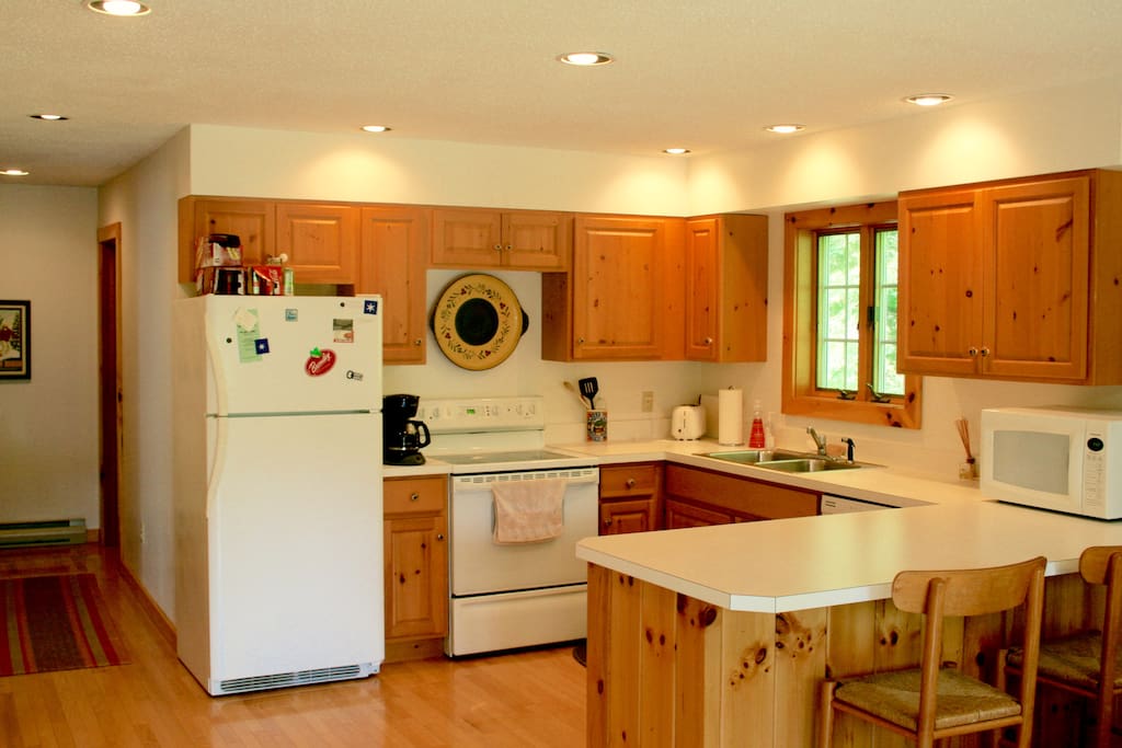 Large, bright kitchen with breakfast bar, fully stocked with flatware, silverware and cookware