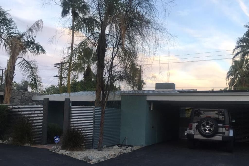 Front of home with original carport, architectural metal sloped roof, solar and private enclosed lockable front patio