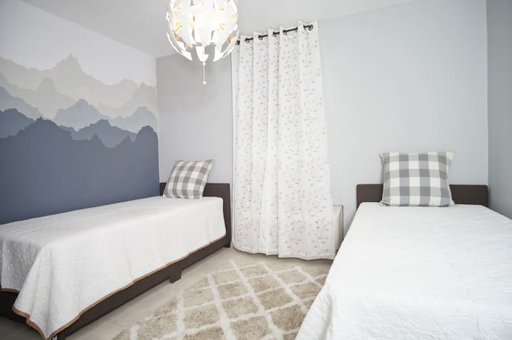Tercer dormitorio | Elegantes camas individuales con pared decorativa.