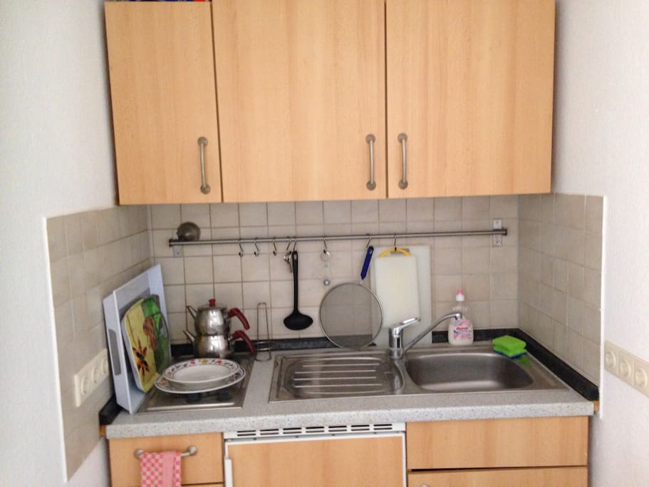 Eine kleine Miniküche mit 2 Herdplatten und Kühlschrank. Ein kleiner Ofen für eine Pizza oder etwas anderes leckeres ist auch vorhanden.