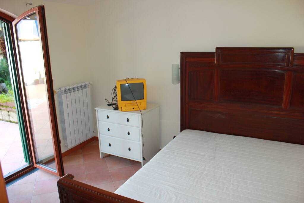 Camera da letto con letto matrimoniale, cassettiera e televisione